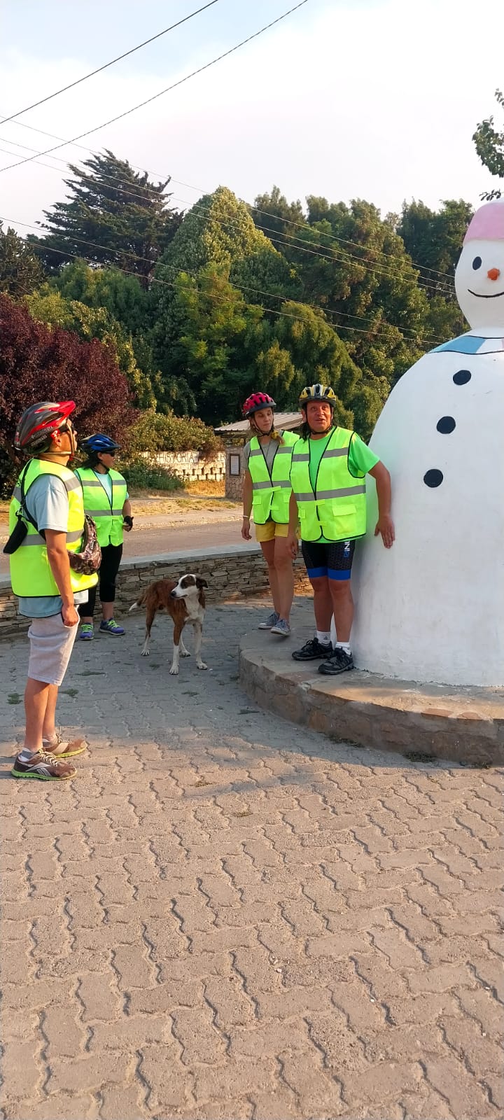 Integrantes de Atreverse con chalecos y cascos posando junto a una estatua de muñeco de nieve en Esquel