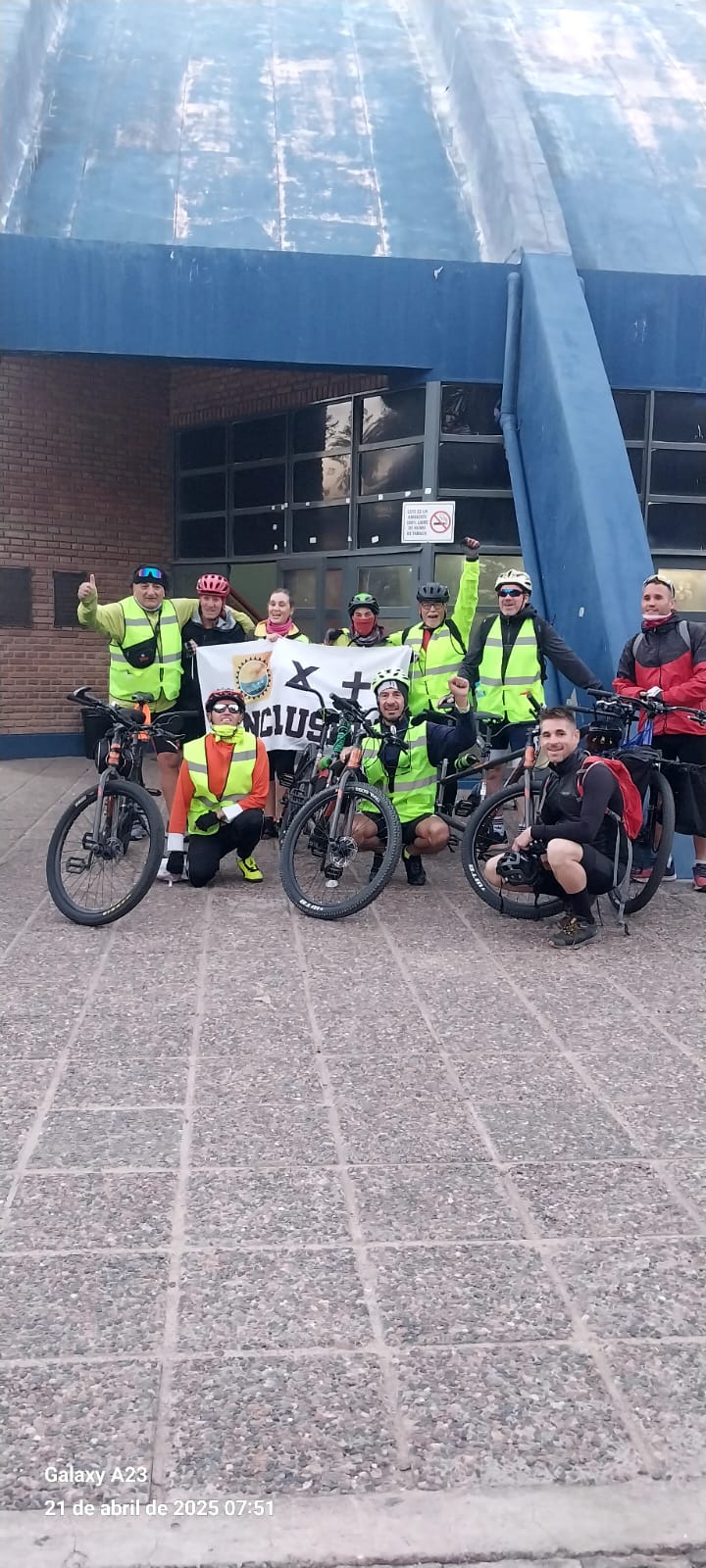 Integrantes de Atreverse posando con su bandera frente a un edificio moderno en Mendoza